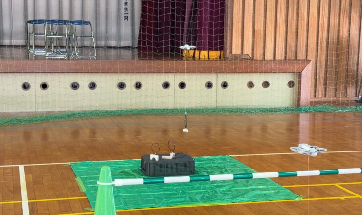 ドローンで積み木を吊り上げ、得点エリアへ運ぶ様子